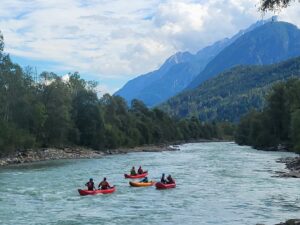 Bild zeigt eine Gruppe von Rafterinnen auf dem Fluss Isel. Im Hintergrund sind die Lienzer Dolomiten.