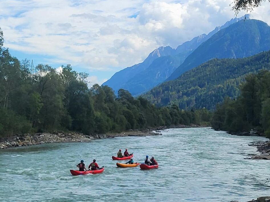 Bild zeigt eine Gruppe von Rafterinnen auf dem Fluss Isel. Im Hintergrund sind die Lienzer Dolomiten.